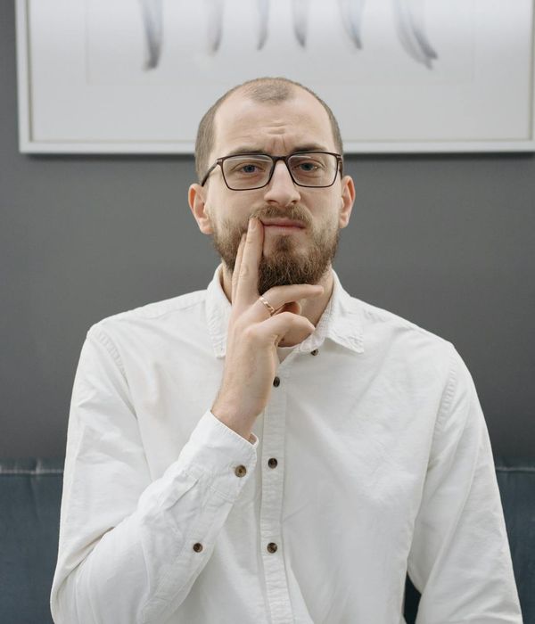 Man in a focused pose in a minimalist dark room, emphasizing concentration.
