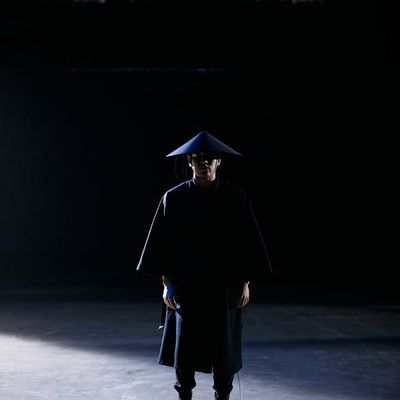 Minimalist kettlebell standing on a dark floor.